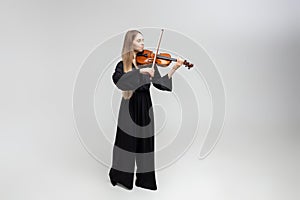 Full length portrait of attractive woman musician playing violin