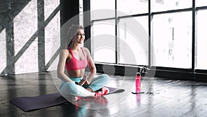 Full length portrait of attractive young woman working out in luxury fitness center, doing yoga or pilates exercise