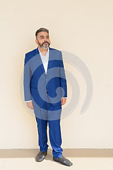 Full length portrait of bearded Indian businessman wearing suit against plain background