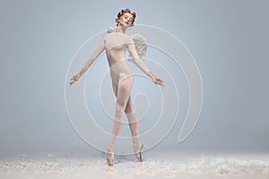 Full-length portrait of beautiful graceful ballerina dancing in image of angel with wings  on gray studio