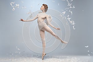 Full-length portrait of beautiful graceful ballerina dancing in image of angel with wings  on gray studio