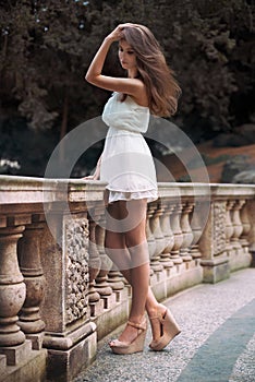 Full length portrait of beautiful model woman with long legs wearing white dress posing oudoors