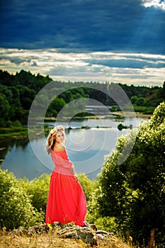 Full length portrait of beautiful sensual young blond woman near the lake outdoors in natural background. girl in long pink dress