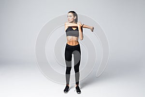 Full length portrait of beautiful young woman doing stretching exercise isolated over gray background