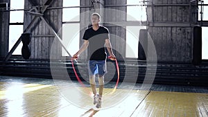 Full length portrait of a boxer jumping with skipping rope. Athletic, muscular young boxer training with jumping rope