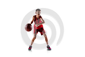 Full-length portrait of boy, basketball player in red uniform training isolated over white background. Defender