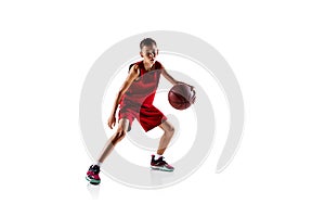 Full-length portrait of boy, basketball player in red uniform training isolated over white background. Dribbling