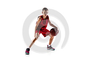 Full-length portrait of boy, basketball player in red uniform training isolated over white background. Dribbling ball