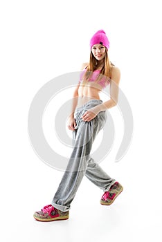 Full-length portrait of carefree girl in gray pants, pink top and hat jumping and dancing. Teen girl hip-hop dancer, over white