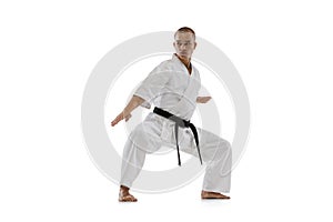 Full-length portrait of caucasian sportsman standing in a fight pose isolated over white background. Karate, judo