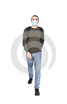 Full length portrait of cautious man wearing face mask as protection against coronavirus, walking towards camera isolated on white