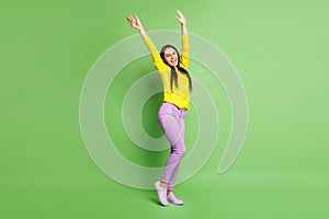 Full length portrait of charming cheerful girl closed eyes raise hands open mouth dance isolated on green color