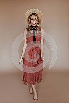 Full-length portrait of charming european woman in canotier. Indoor photo of magnificent lady in straw hat and dress..