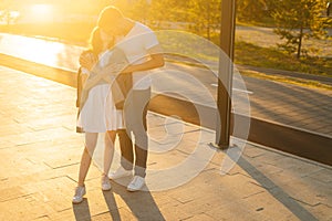 Full length portrait of charming young couple in love kissing hugging in summer evening on background of warm sunlight.