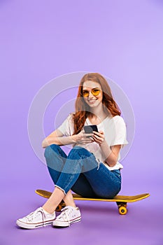 Full length portrait of a cheerful young girl in sunglasses