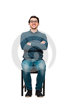 Full length portrait of confident businessman seated on a chair, wearing eyeglasses and keeps arms crossed, isolated on white