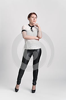 Full length portrait of confident businesswoman looking at camera with one hand raised to chin