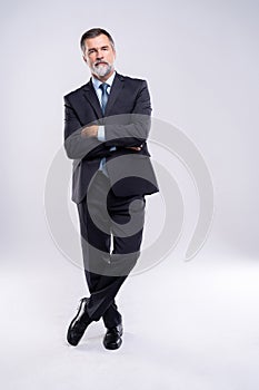 Full length portrait of confident mature businessman in formals standing isolated over white background.