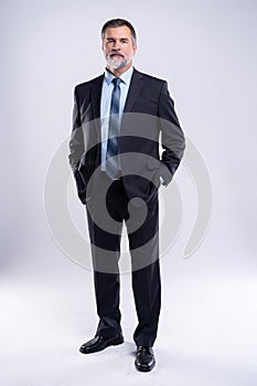 Full length portrait of confident mature businessman in formals standing isolated over white background.