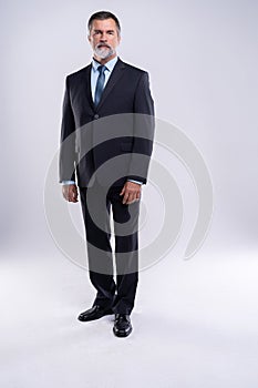 Full length portrait of confident mature businessman in formals standing isolated over white background.