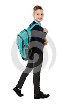 Full length portrait of cute boy in school uniform with backpack on white
