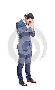 Full length portrait of depressed businessman keeps hands together as prayer, eyes closed, head down isolated on white background
