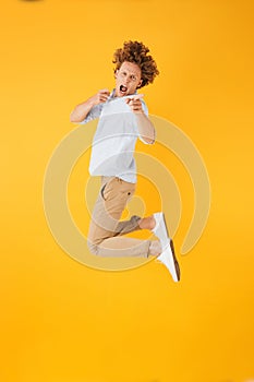 Full length portrait of european happy man 20s jumping and point