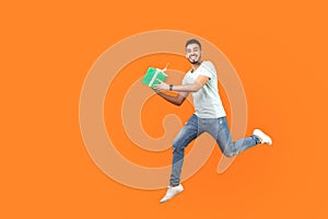 Full length portrait of excited joyous brunette man flying or running in air with gift box, present. studio shot isolated on