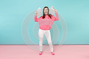Full length portrait excited woman in knitted rose sweater, white pants holding lots dollars banknotes isolated on