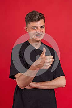 Full length portrait of an excited young man in white t-shirt jumping while celebrating success isolated over red background.