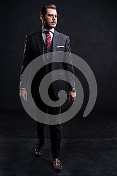 Full length portrait of a fashion male model over black background. Looking at camera.