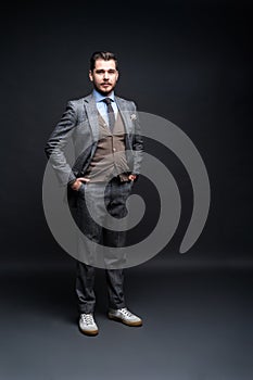 Full length portrait of a fashion male model over black background. Looking at camera.