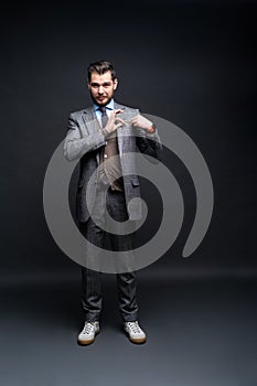 Full length portrait of a fashion male model over black background. Looking at camera.