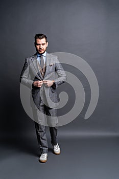 Full length portrait of a fashion male model over grey background. Looking at camera.