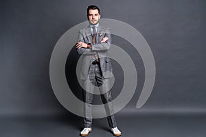 Full length portrait of a fashion male model over grey background. Looking at camera.