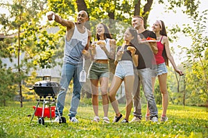 Full-length portrait of five friends spending time together outside city and taking selfie on warm summer day