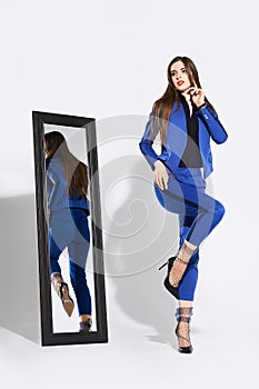 Full length portrait of a  girl in pantsuit and tulle socks near the mirror looking to the side