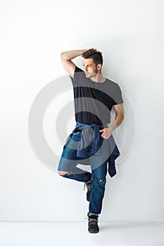 Full length portrait of handsome stylish man leaning at white wa