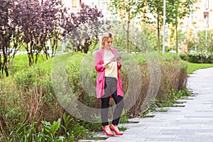 Full length portrait of happy beautiful young successful blogger businesswoman in elegance style standing on green park, holding