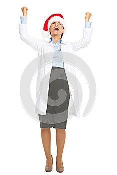 Full length portrait of happy doctor woman in santa hat rejoicing