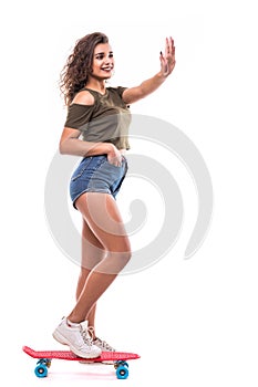 Full length portrait of a happy excited woman riding a skateboard wave to someone isolated over white background