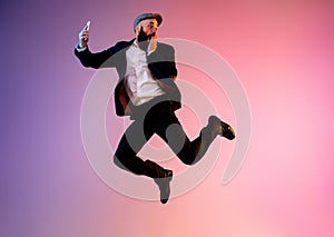 Full length portrait of happy jumping man in neon light and gradient background