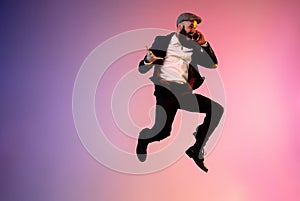 Full length portrait of happy jumping man in neon light and gradient background