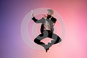 Full length portrait of happy jumping man in neon light and gradient background