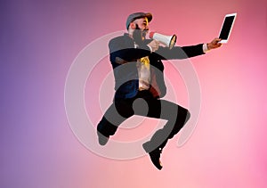 Full length portrait of happy jumping man in neon light and gradient background