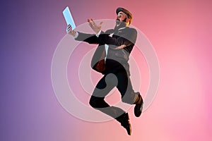 Full length portrait of happy jumping man in neon light and gradient background