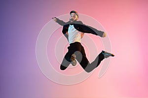 Full length portrait of happy jumping man in neon light and gradient background