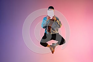 Full length portrait of happy jumping man in neon light and gradient background