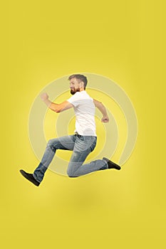Full length portrait of happy jumping man on yellow background