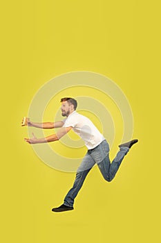 Full length portrait of happy jumping man on yellow background